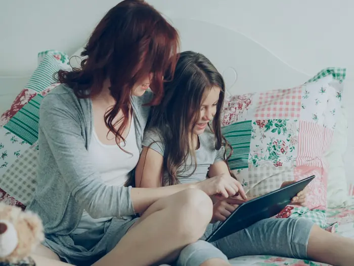 A mom and her daughter looking at a tablet together